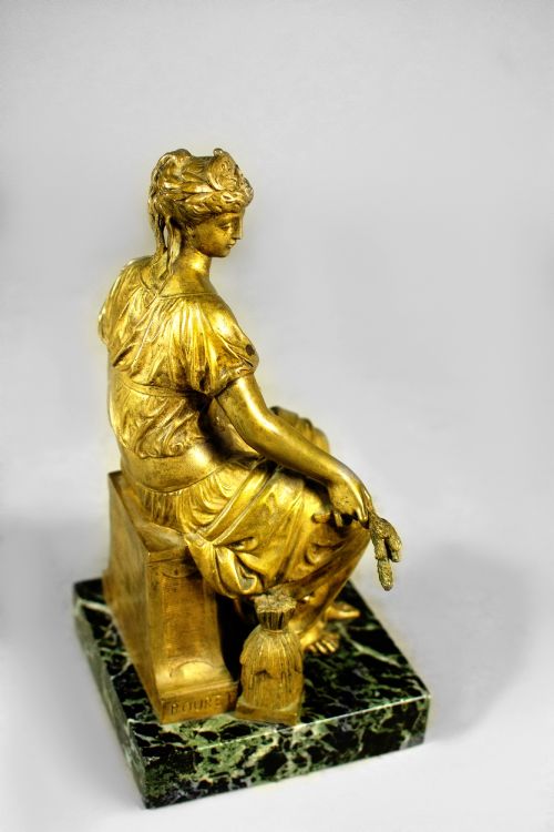 fig 1. A nineteenth-century gilt bronze sculpture depicting the seated Roman goddess Ceres holding a sheaf of wheat on a square green marble base.