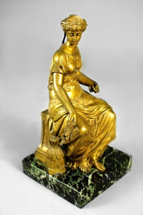 fig 3. A nineteenth-century gilt bronze sculpture depicting the seated Roman goddess Ceres holding a sheaf of wheat on a square green marble base.