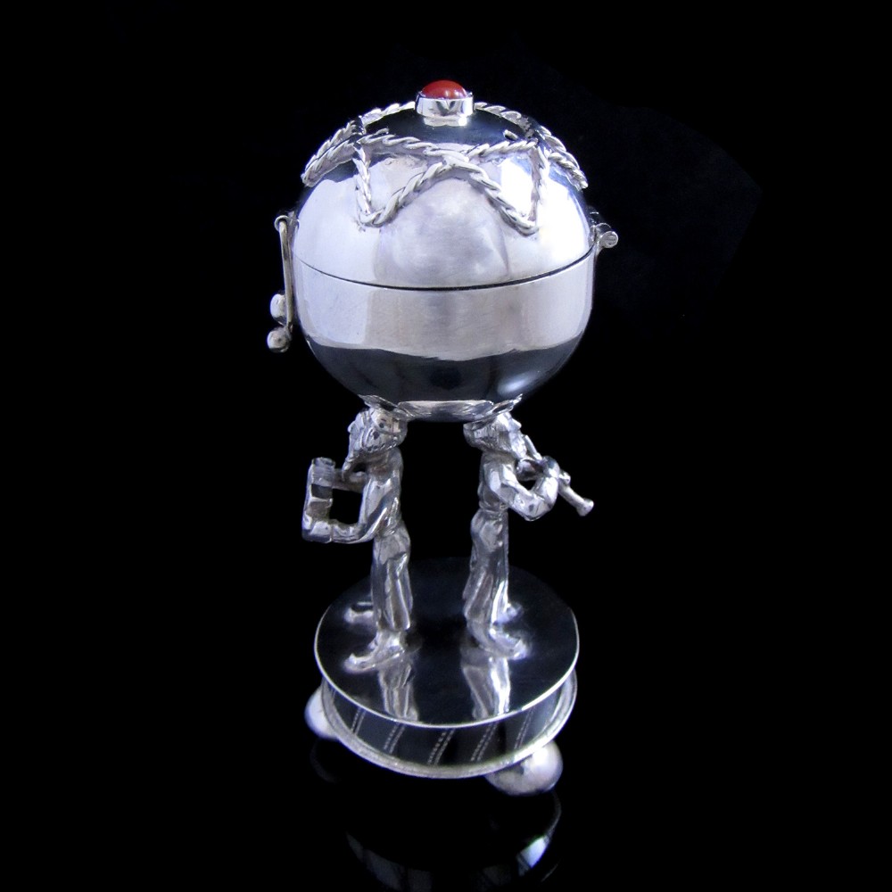 A late 19th-century Russian solid silver Judaica spice box with a spherical container topped with a red cabochon stone, supported by two silver figures on a circular base.