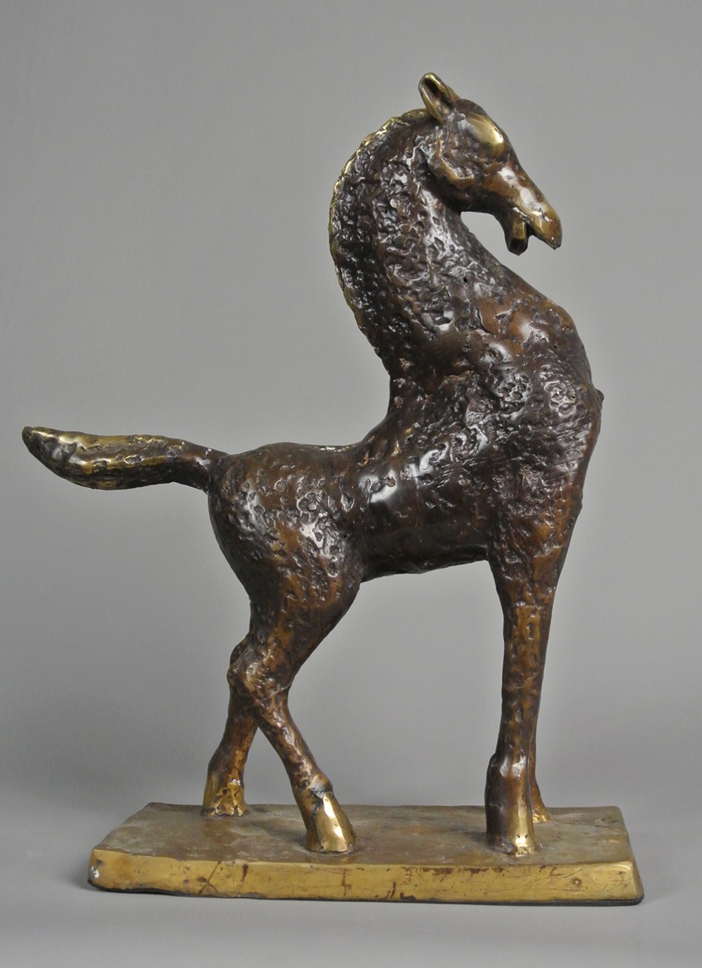 An early 20th-century textured bronze sculpture of a stylized standing horse on an integral rectangular base.