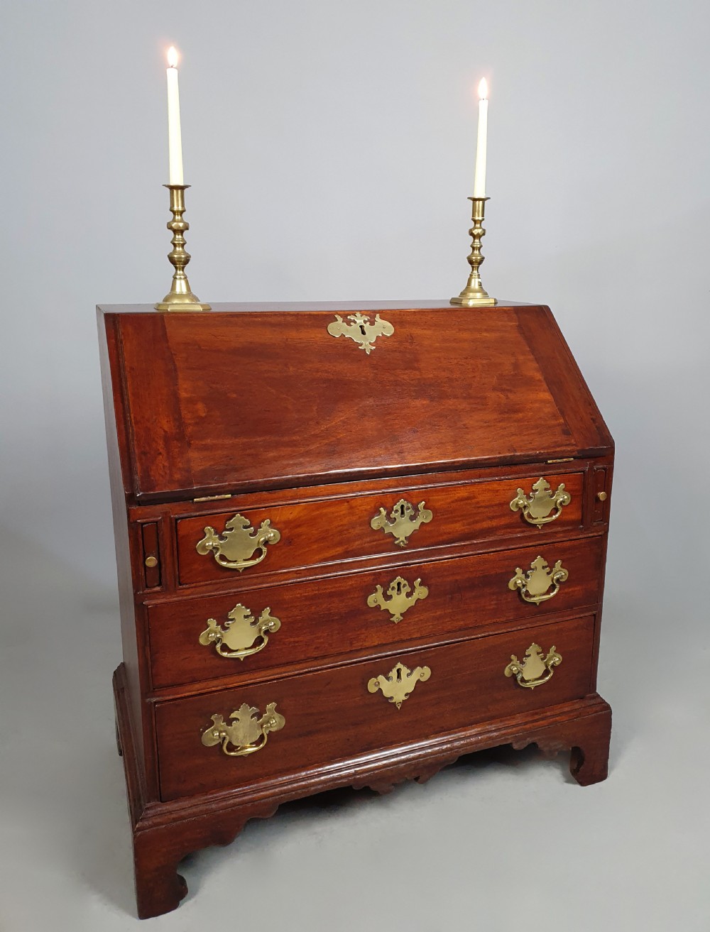 An 18th-century George II fruitwood slant-front bureau shown open, displaying fitted internal pigeonholes, small drawers, and brass hardware. View III