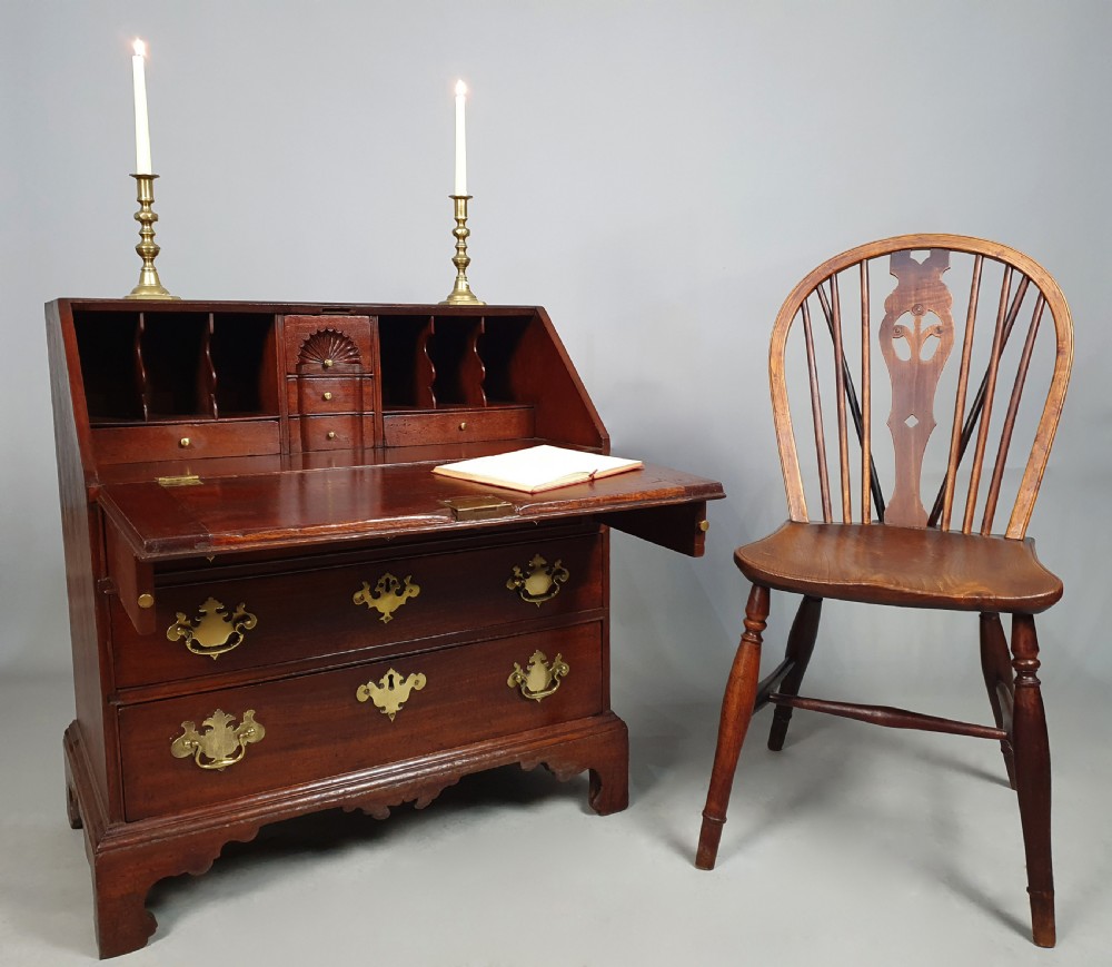 An 18th-century George II fruitwood slant-front bureau shown open, displaying fitted internal pigeonholes, small drawers, and brass hardware. View IV