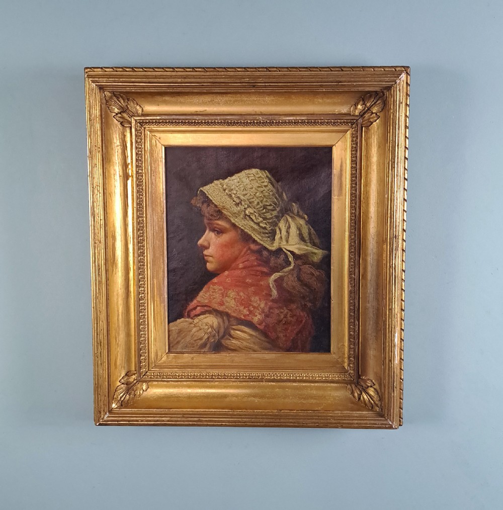A 19th-century Victorian oil portrait on canvas depicting a young woman in profile wearing a lace bonnet and red shawl, enclosed in an ornate gilded frame.