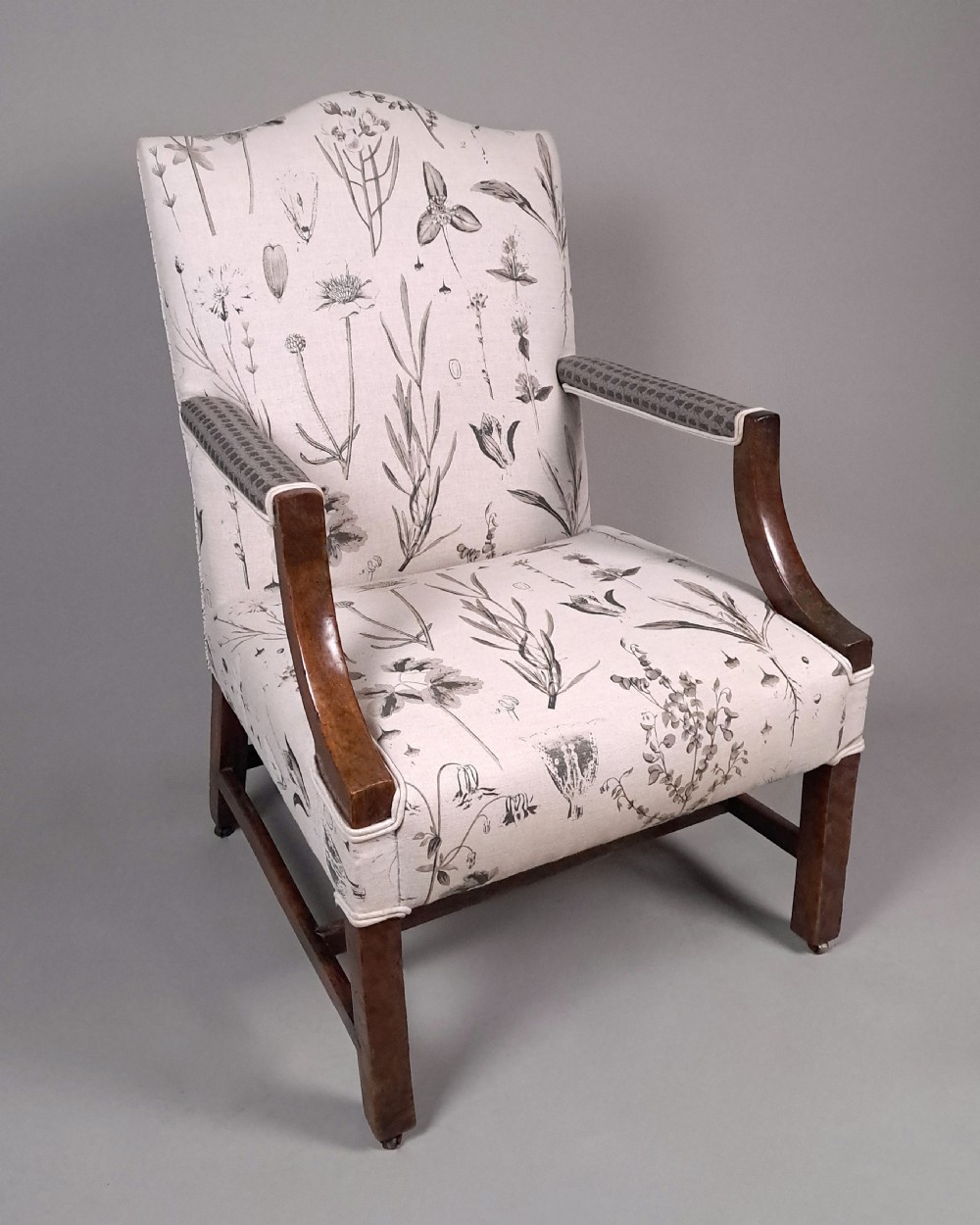 A George III yew wood Gainsborough armchair featuring monochrome botanical fabric upholstery, padded armrests, square legs, and brass castors. View IV