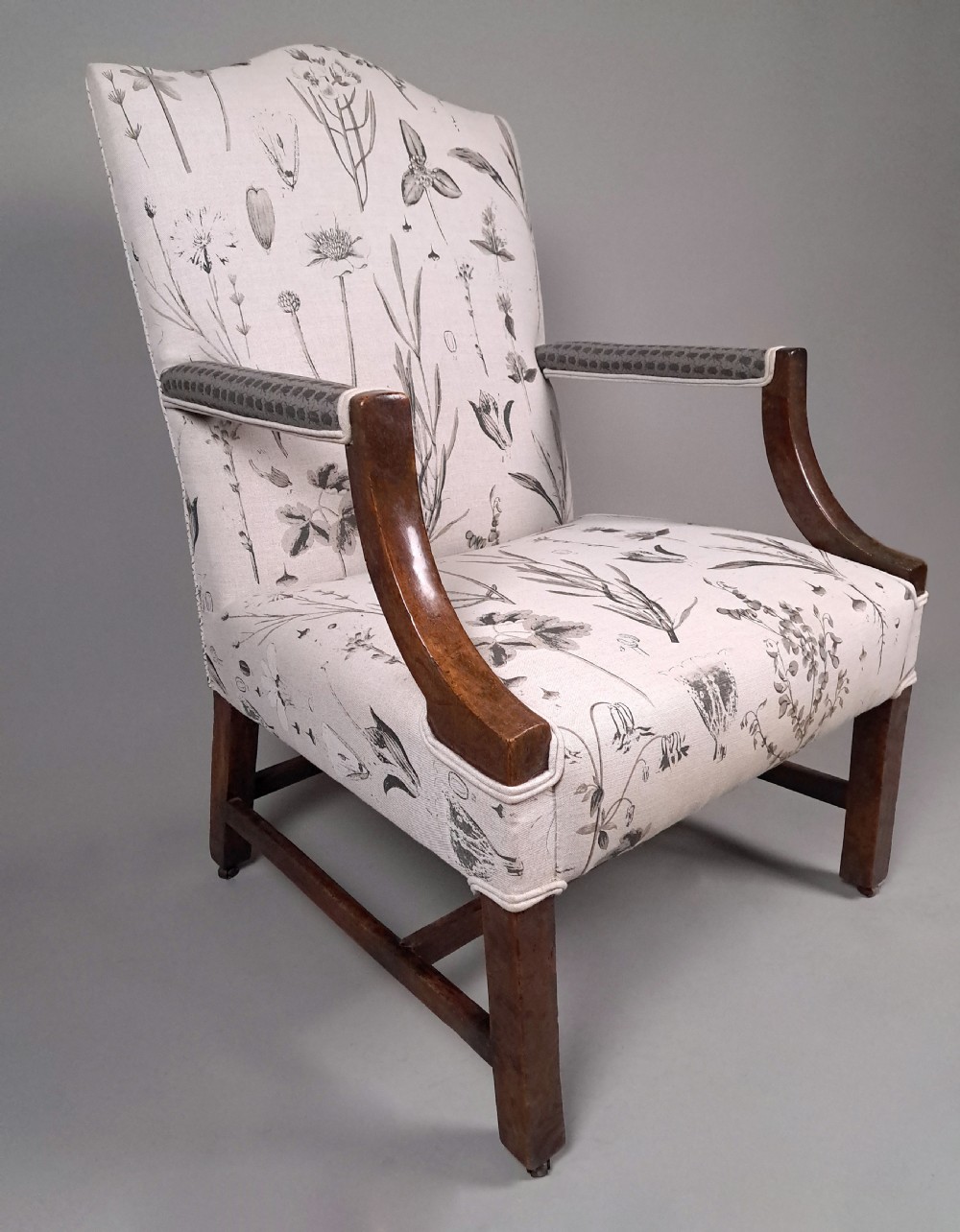 A George III yew wood Gainsborough armchair featuring monochrome botanical fabric upholstery, padded armrests, square legs, and brass castors. View V