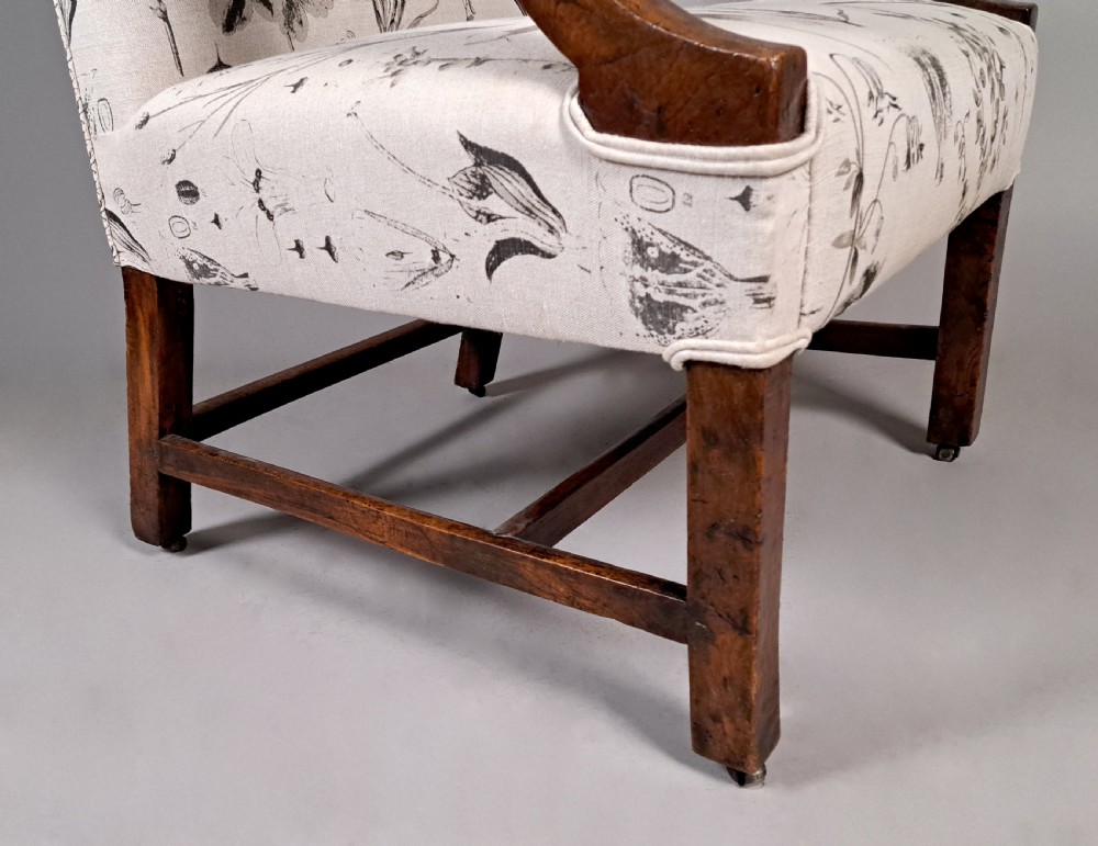 A George III yew wood Gainsborough armchair featuring monochrome botanical fabric upholstery, padded armrests, square legs, and brass castors. View IX