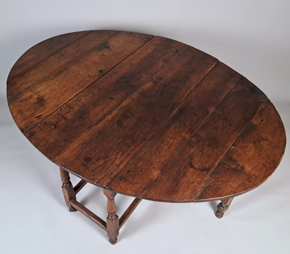 An early 18th-century oak gateleg table featuring an oval drop-leaf top, turned baluster legs, and lower box stretchers. View III