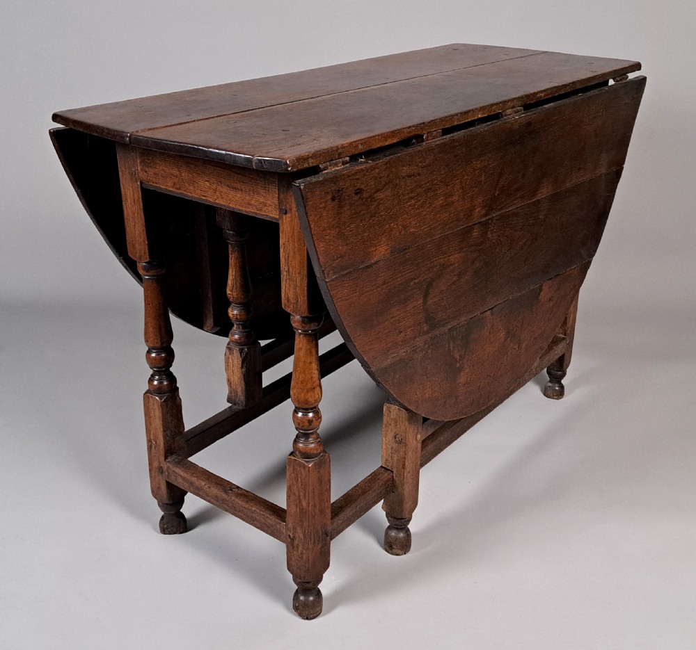An early 18th-century oak gateleg table featuring an oval drop-leaf top, turned baluster legs, and lower box stretchers. View IV