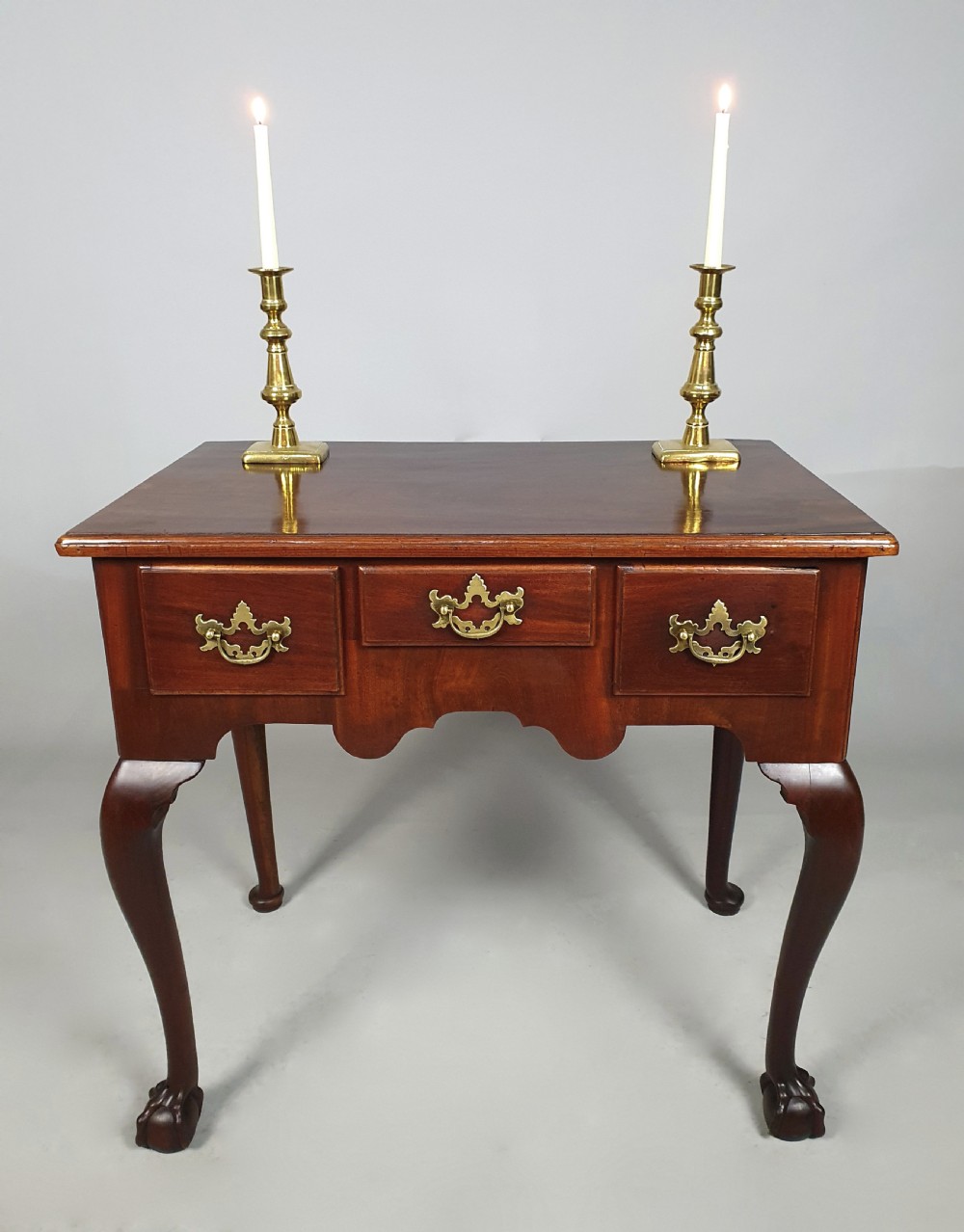 An 18th-century George III red walnut lowboy table with three brass-handled drawers, a shaped apron, and front cabriole legs ending in carved ball-and-claw feet. View IV