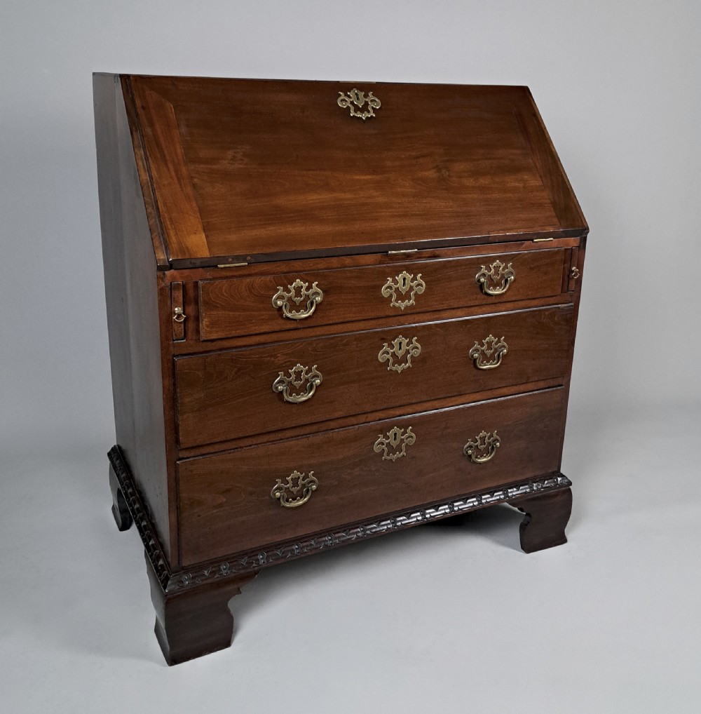 An eighteenth-century Chippendale style dark padauk wood writing bureau featuring an open fall-front writing surface, architectural pigeonhole section, brass handles, and bracket feet. View II