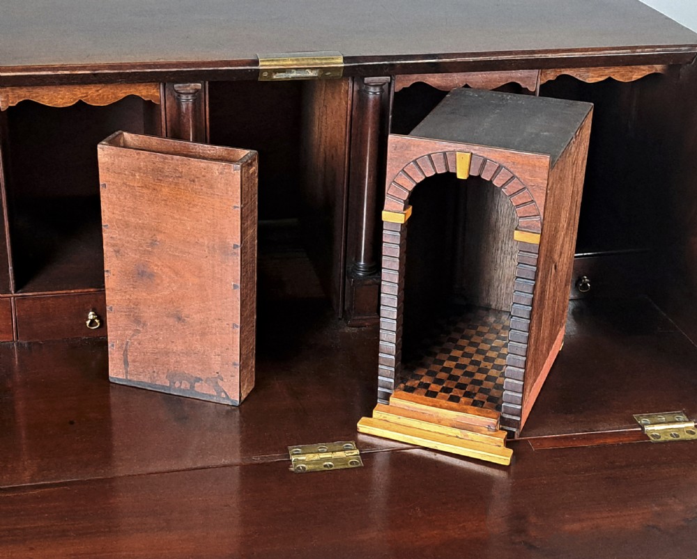 An eighteenth-century Chippendale style dark padauk wood writing bureau featuring an open fall-front writing surface, architectural pigeonhole section, brass handles, and bracket feet. View VI