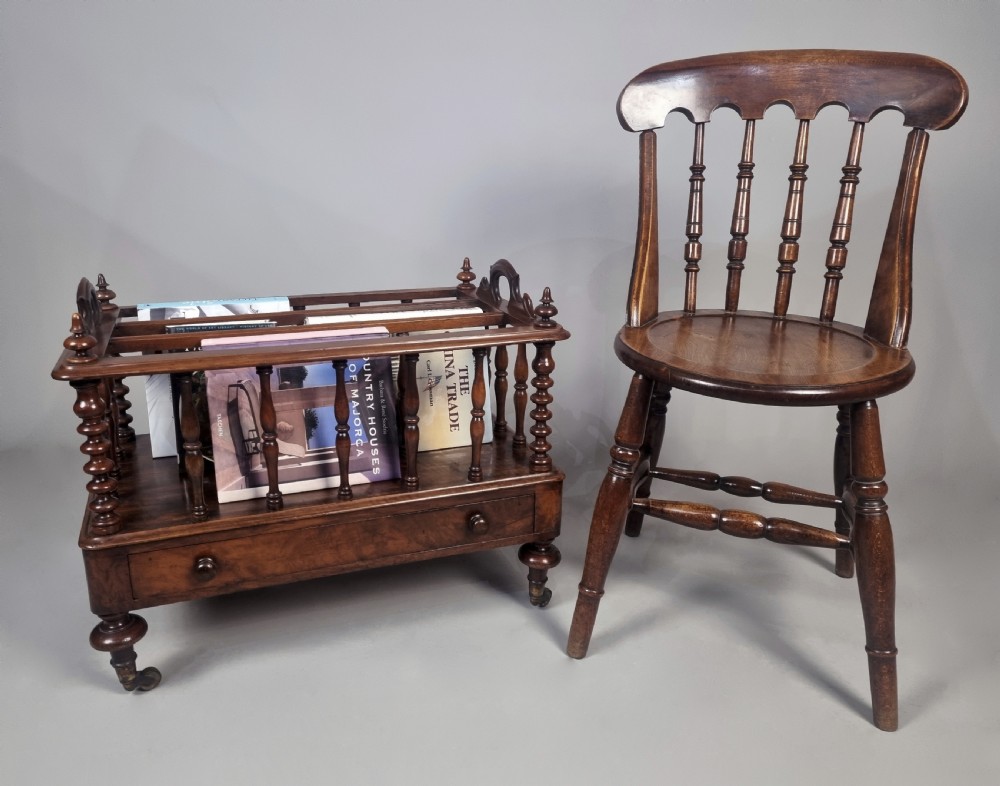 A Victorian walnut music Canterbury featuring turned spindles, division compartments, a lower drawer with twin knobs, and turned legs with brass castors. View II