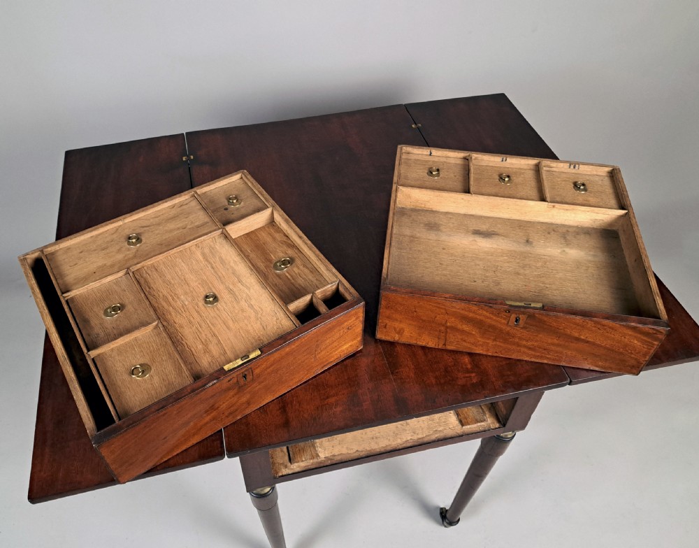 A George III mahogany campaign table with a split hinged top, flame mahogany drawer front, brass collar mounts, turned tapering legs, and brass castors. View III