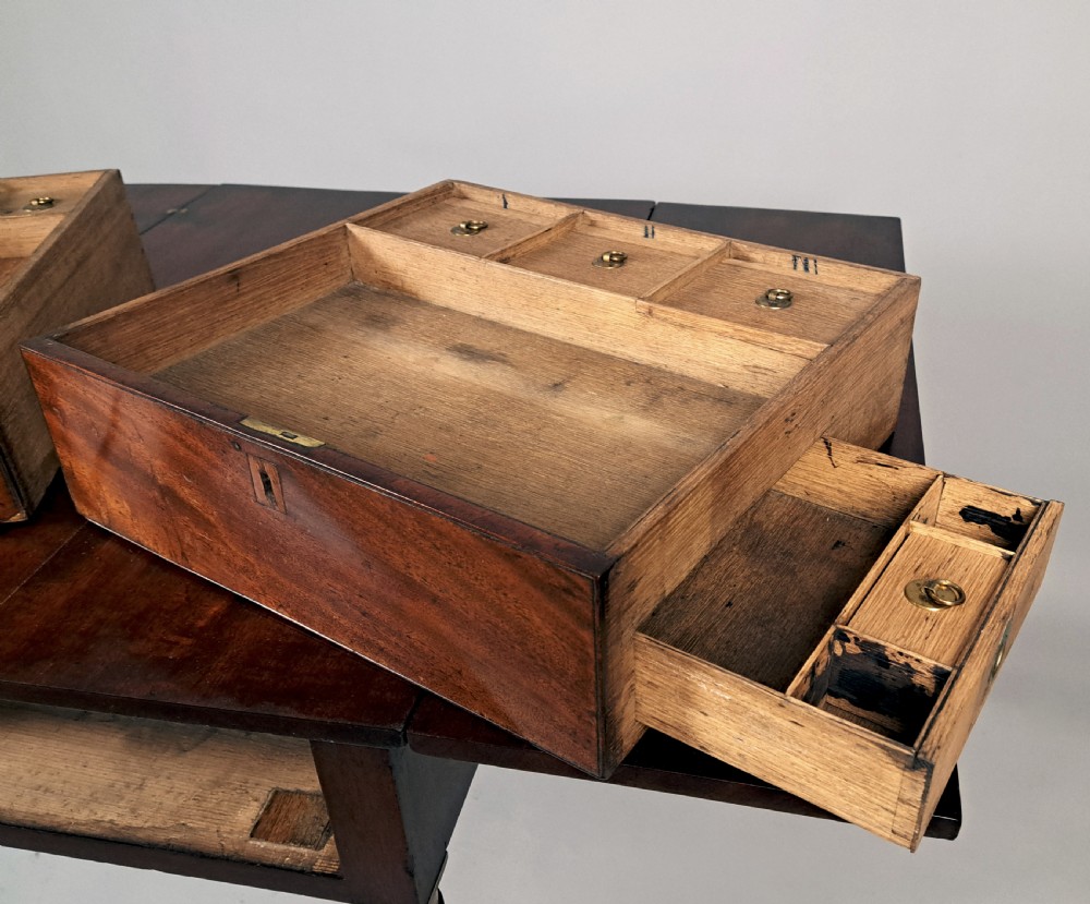 A George III mahogany campaign table with a split hinged top, flame mahogany drawer front, brass collar mounts, turned tapering legs, and brass castors. View IV