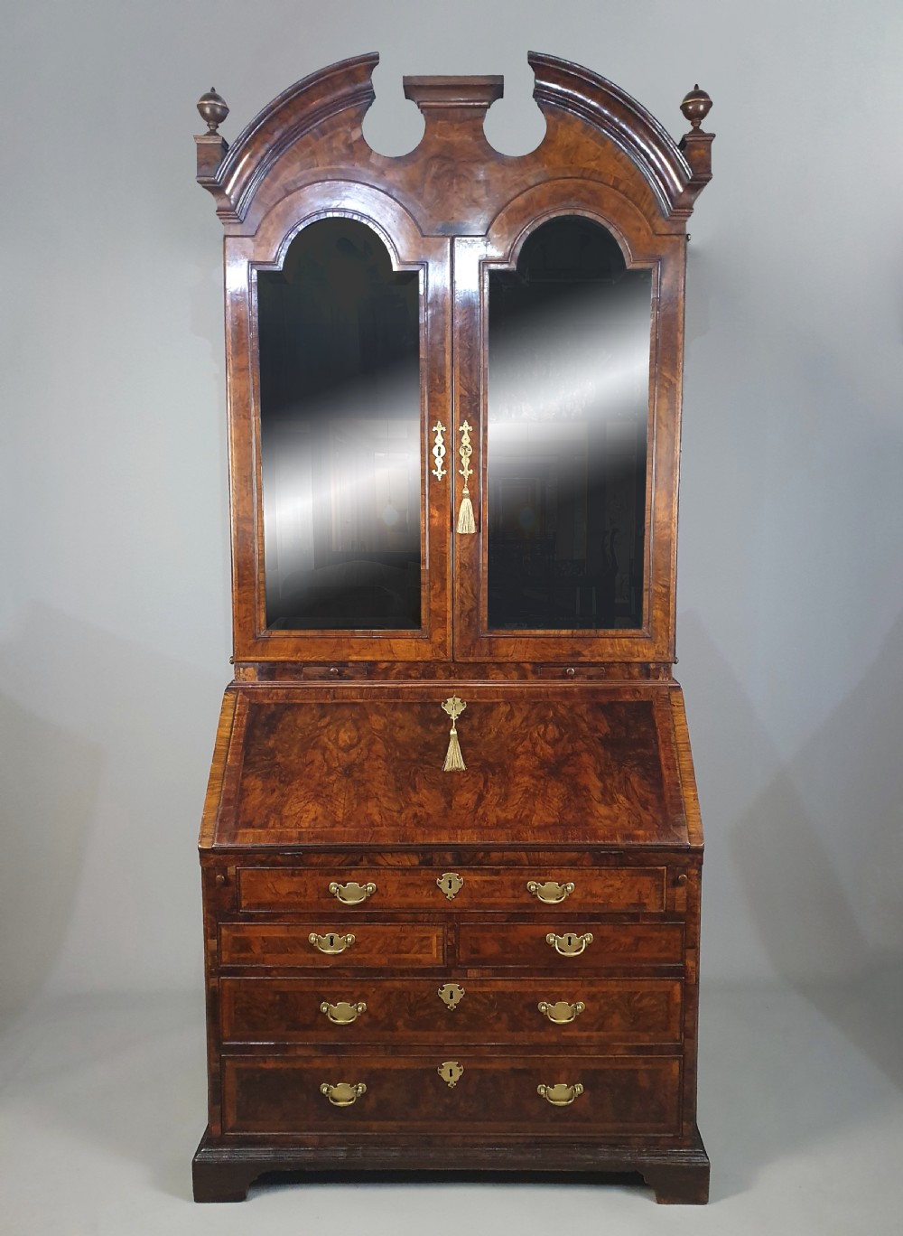 An early 18th-century Queen Anne burr walnut bureau cabinet featuring a double-domed pediment, open doors revealing multiple pigeonholes, a sloped drop-front writing desk, and lower storage drawers. View III