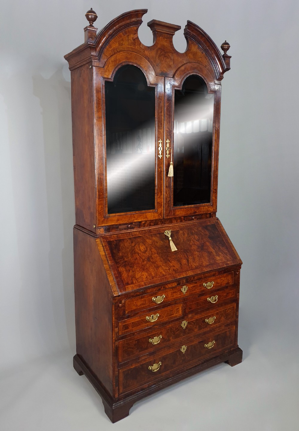 An early 18th-century Queen Anne burr walnut bureau cabinet featuring a double-domed pediment, open doors revealing multiple pigeonholes, a sloped drop-front writing desk, and lower storage drawers. View VII