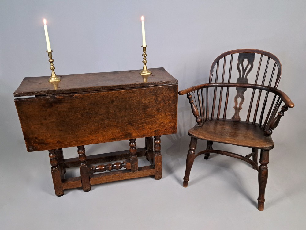 A 17th-century Charles II dark oak drop-leaf side table featuring turned legs, a hinged top flap, and sturdy lower stretchers. View II