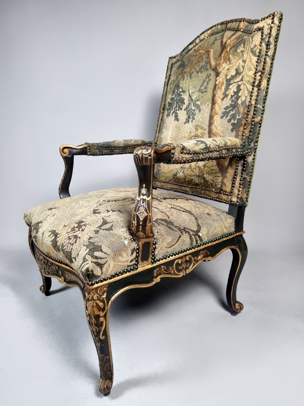 A George III Gainsborough armchair with carved cabriole legs, parcel gilding, and green landscape tapestry upholstery trimmed with brass studs. View VII