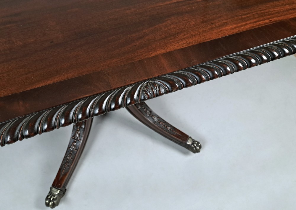 A George III mahogany dining table featuring a rectangular top with carved rope-twist edging, resting on a turned central column and four carved legs with brass castors. View II