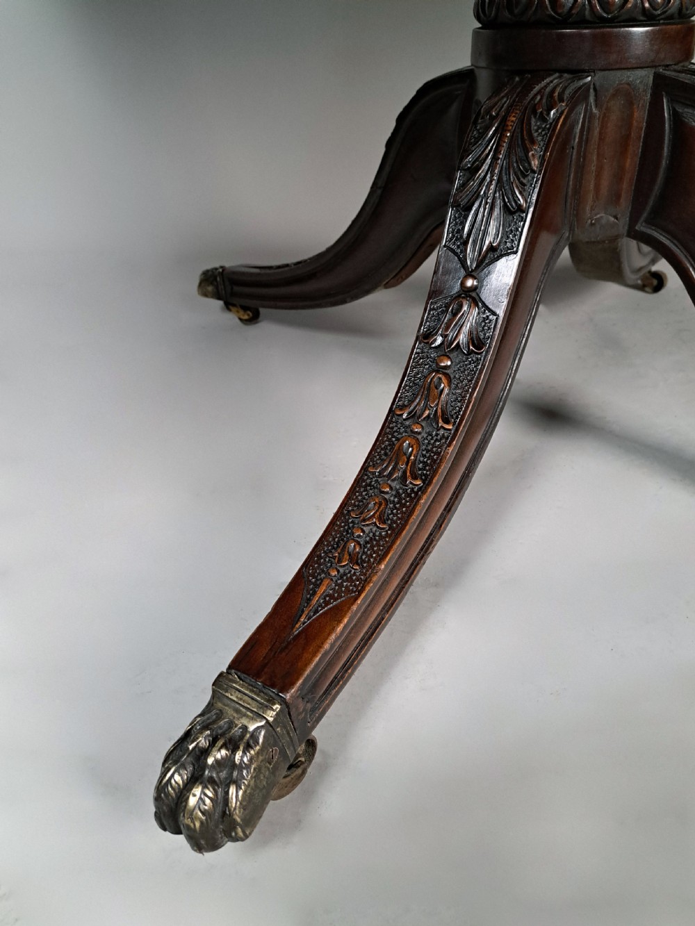 A George III mahogany dining table featuring a rectangular top with carved rope-twist edging, resting on a turned central column and four carved legs with brass castors. View III