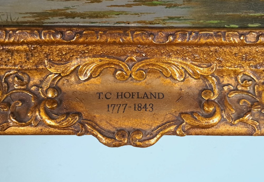 An early 19th-century English oil on board landscape painting depicting a pastoral river scene with cattle and castle ruins, housed within an ornate gold giltwood frame. View III