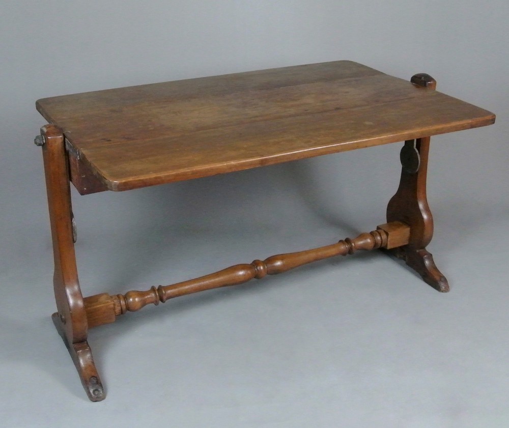 A Georgian solid teak campaign table featuring a rectangular tilt-top surface supported by shaped side trestles connected by a central turned stretcher.