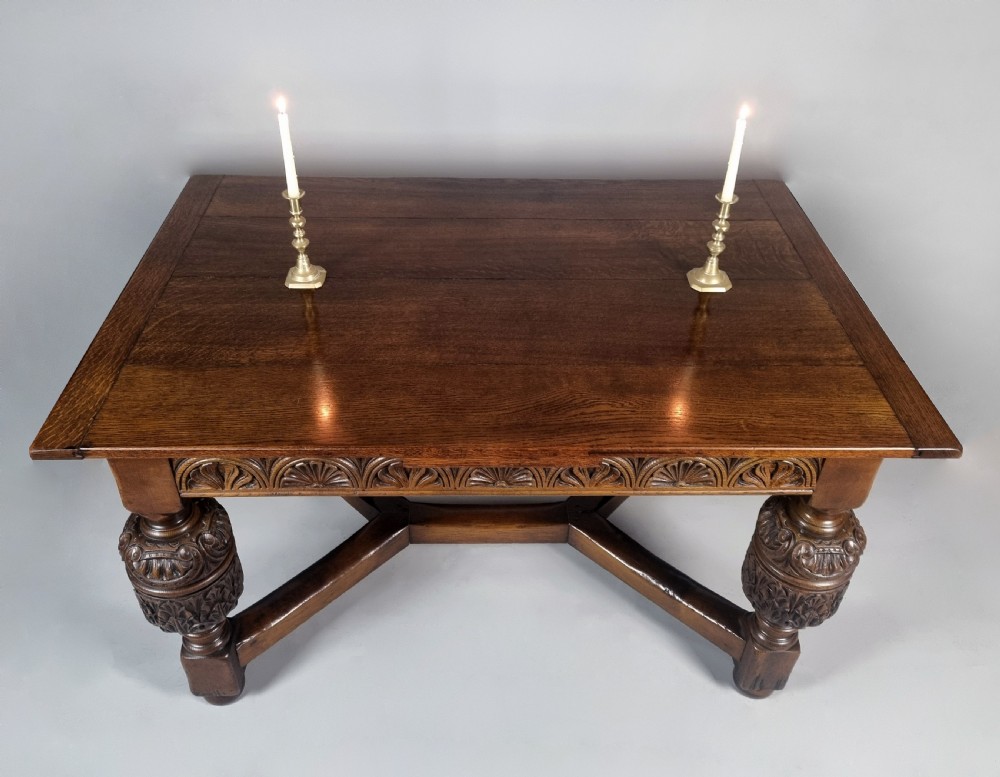 A carved warm brown oak extending dining table featuring heavy bulbous cup-and-cover legs, carved frieze detailing, and a floor stretcher base. View II