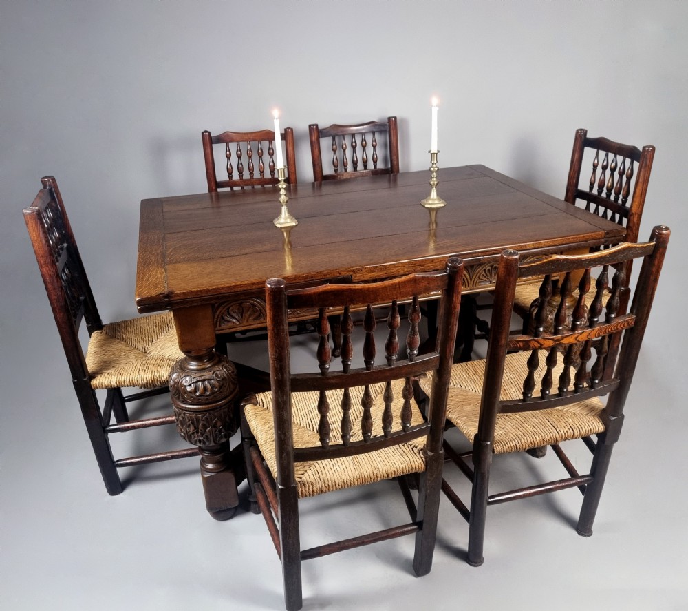 A carved warm brown oak extending dining table featuring heavy bulbous cup-and-cover legs, carved frieze detailing, and a floor stretcher base. View VI
