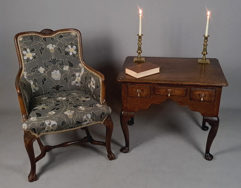 A 19th-century Queen Anne revival armchair featuring patterned grey floral upholstery, curved wings, shell carved top crest, and cabriole timber legs. View II