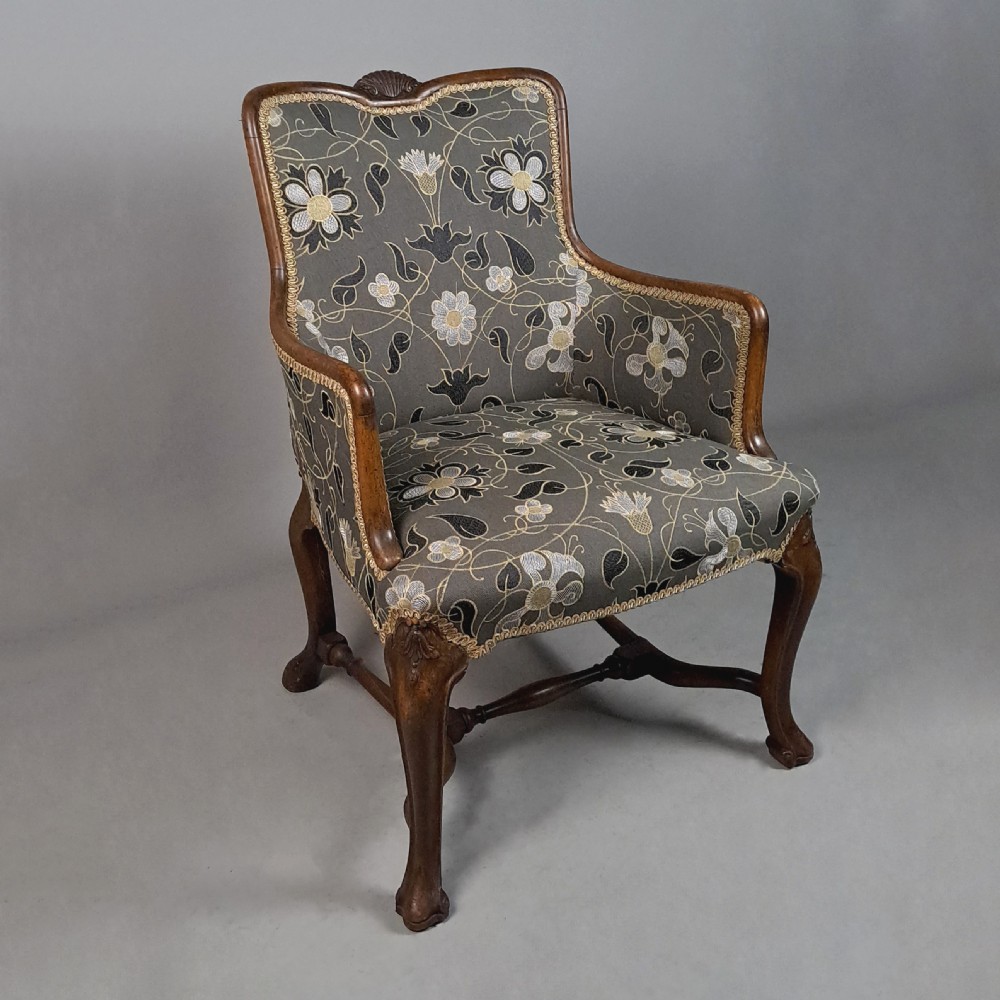 A 19th-century Queen Anne revival armchair featuring patterned grey floral upholstery, curved wings, shell carved top crest, and cabriole timber legs. View III