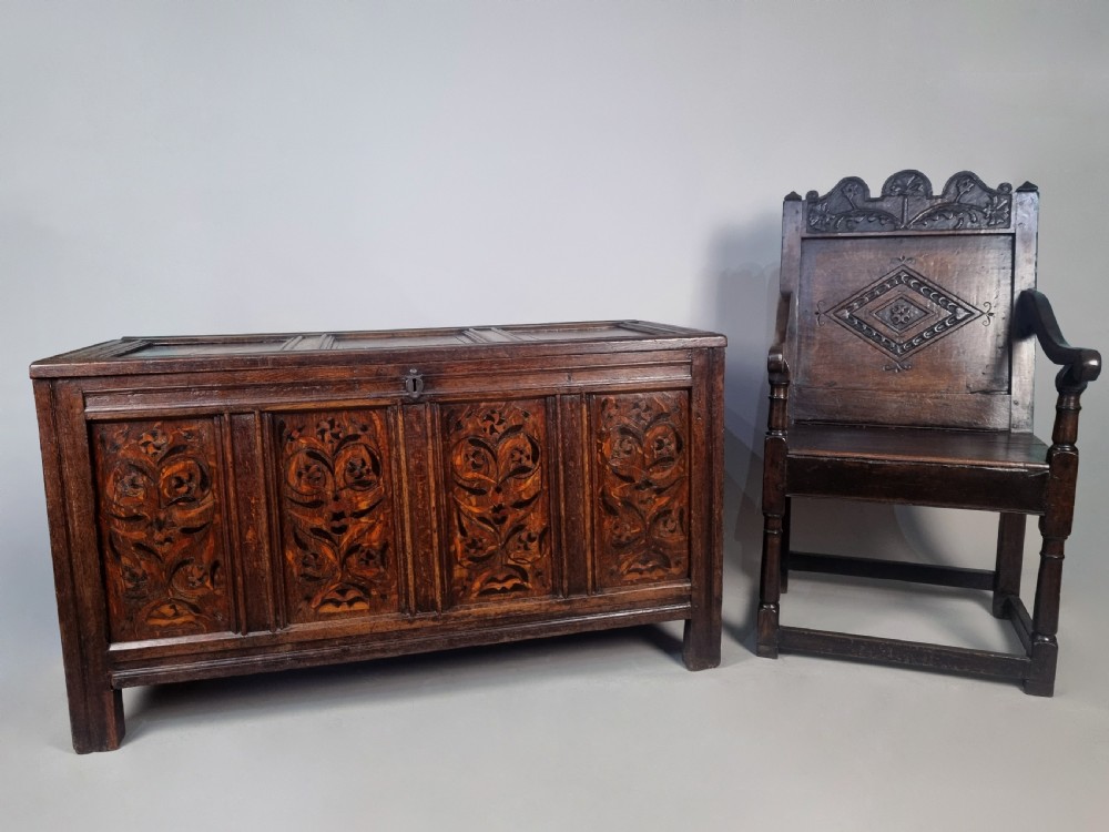 A 17th-century dark oak chest featuring four front panels with intricate floral marquetry inlay, a panelled top, and an iron keyhole. View IV