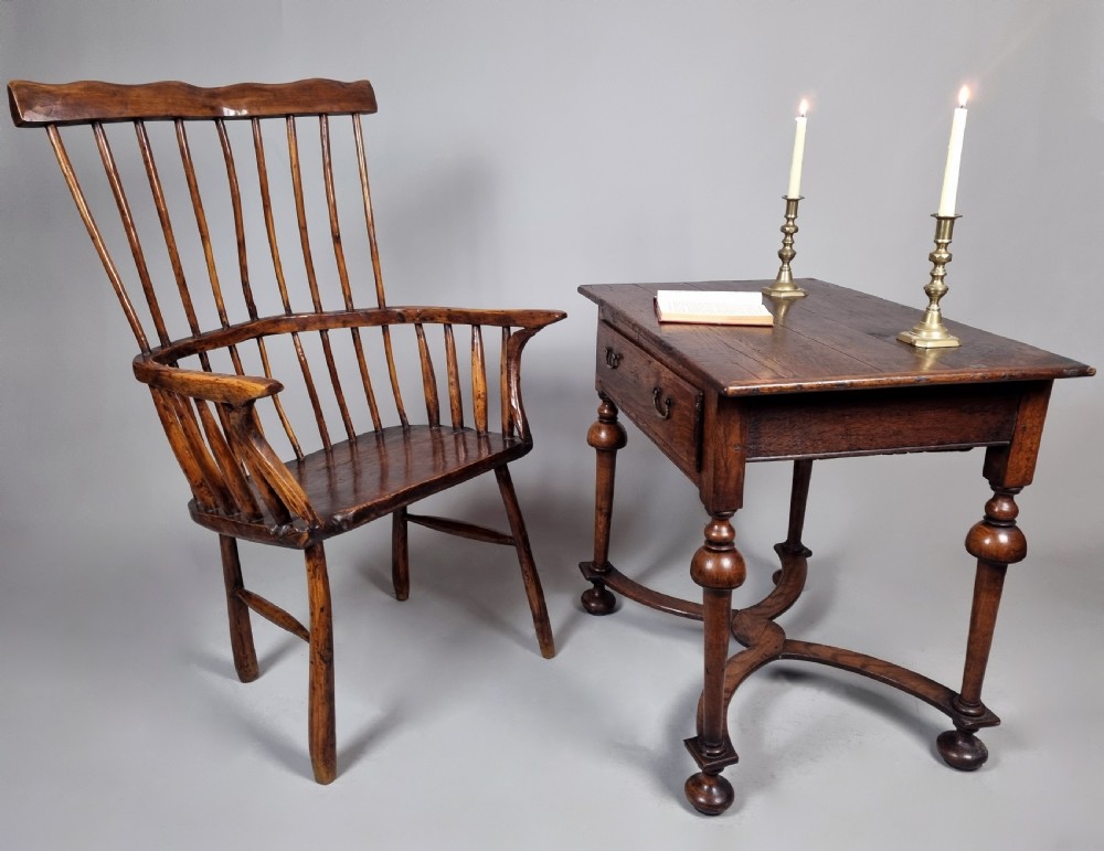 A primitive 18th-century Welsh stick armchair made from dark polished wood featuring a comb back, tapered stick spindles, and an organic curved frame. View IV