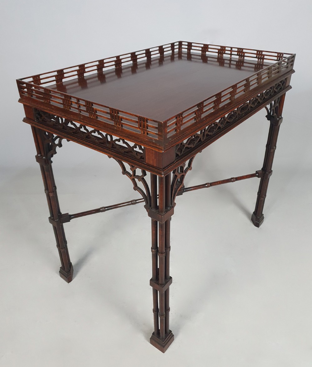 A dark padauk wood silver table featuring a rectangular top surrounded by a lattice gallery rim, supported by pierced Gothic arches and cluster column legs.