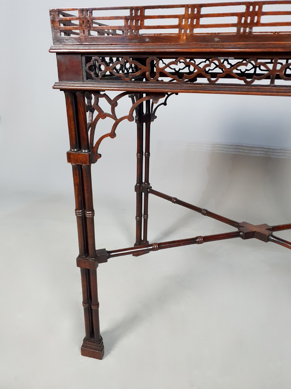 A dark padauk wood silver table featuring a rectangular top surrounded by a lattice gallery rim, supported by pierced Gothic arches and cluster column legs. View IV