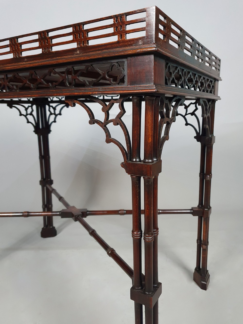 A dark padauk wood silver table featuring a rectangular top surrounded by a lattice gallery rim, supported by pierced Gothic arches and cluster column legs. View VI