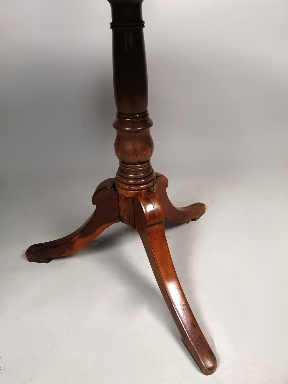 A Georgian yew wood wine table featuring a circular tilt top displaying natural grain patterns, set on a turned central pedestal with three splayed legs. View V