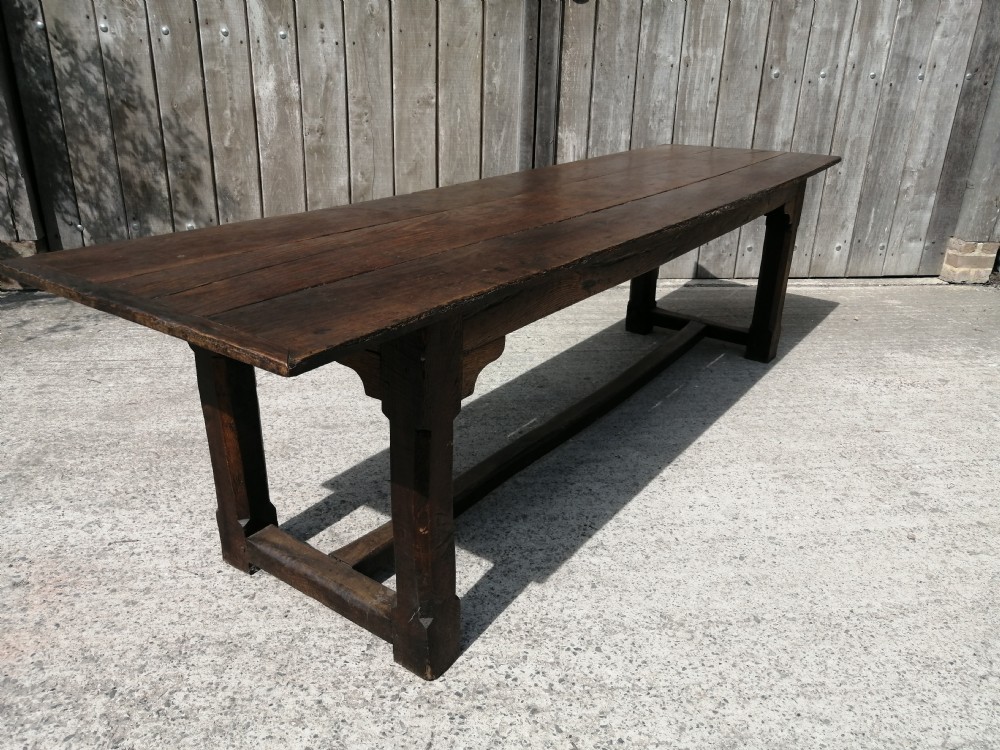 An early eighteenth-century long oak and elm refectory table top showing four wide wooden planks with natural grain, splits, and deep dark patination. View IV
