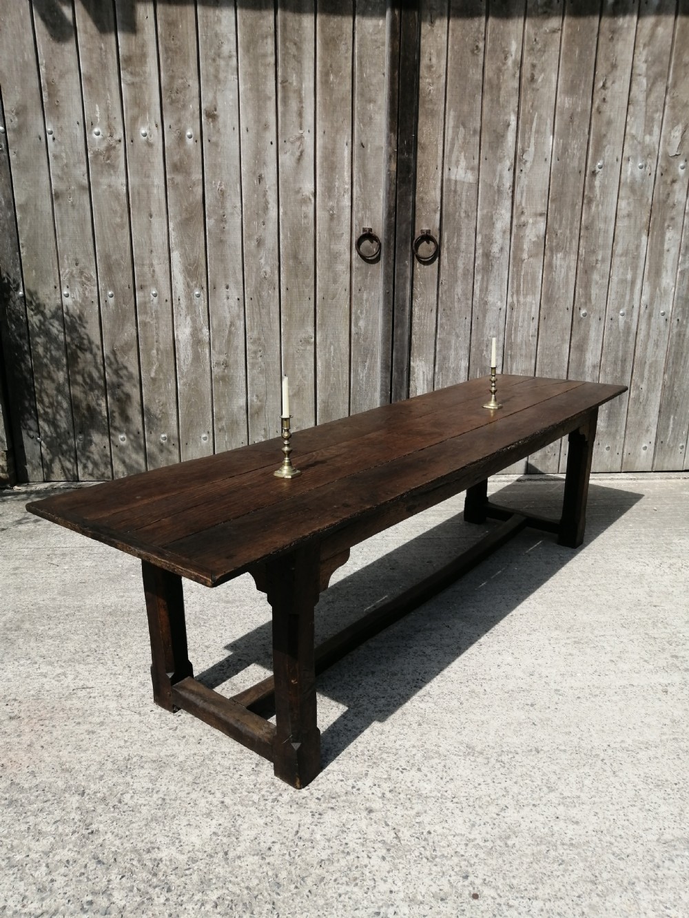 An early eighteenth-century long oak and elm refectory table top showing four wide wooden planks with natural grain, splits, and deep dark patination. View II