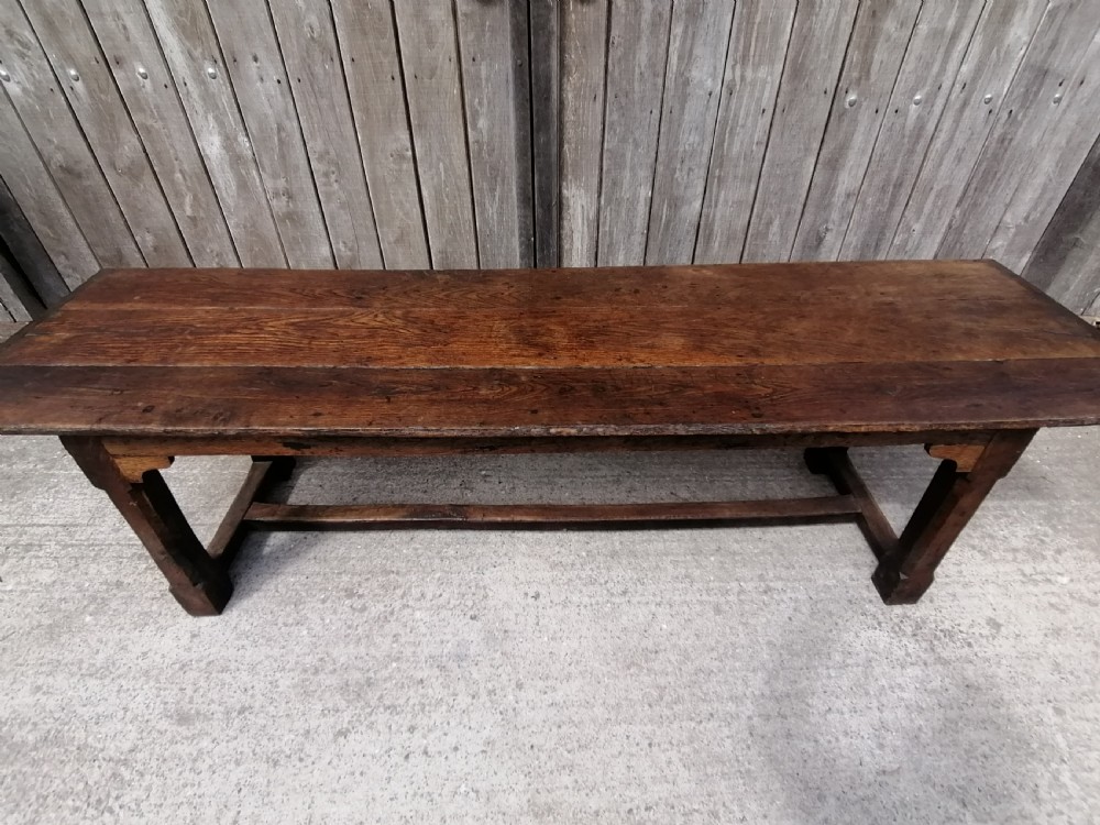 An early eighteenth-century long oak and elm refectory table top showing four wide wooden planks with natural grain, splits, and deep dark patination. View V