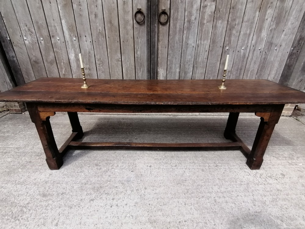 An early eighteenth-century long oak and elm refectory table top showing four wide wooden planks with natural grain, splits, and deep dark patination. View VI