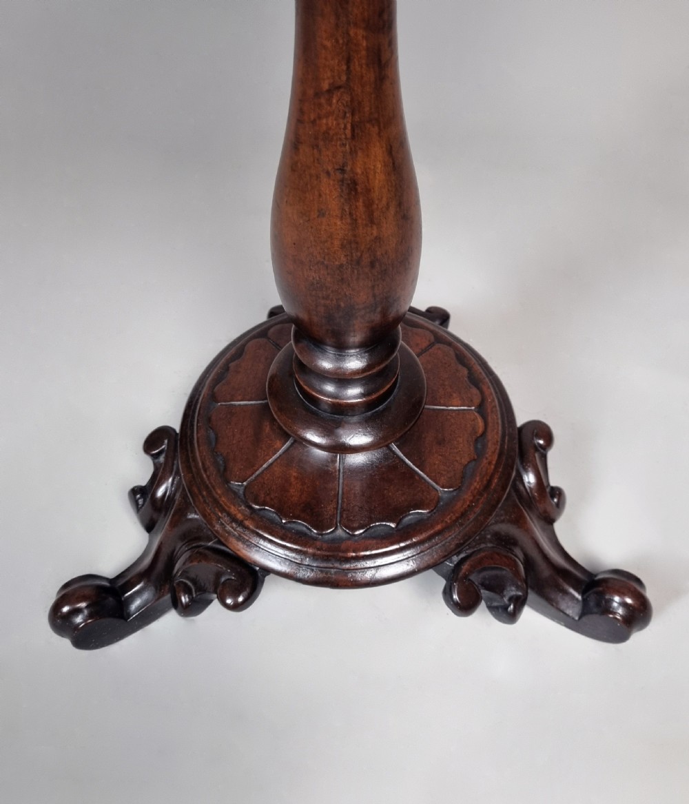 A William IV mahogany wine table featuring a dished circular top, turned central pedestal column, and a carved triform base with scroll feet. View IV