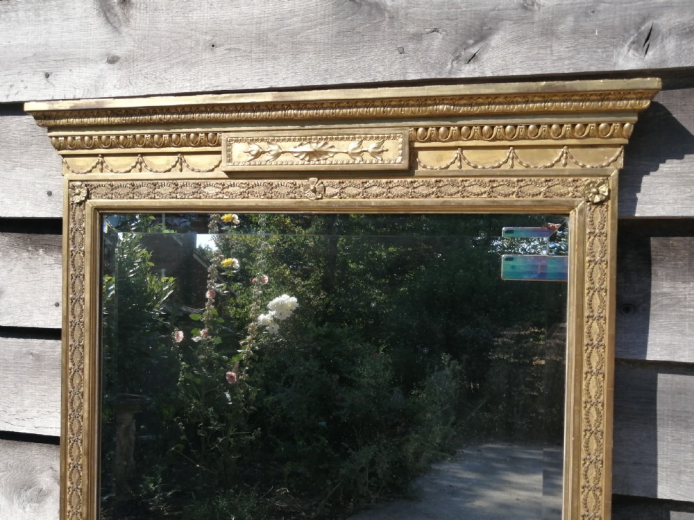 A tall rectangular Regency giltwood pier mirror featuring a carved classical frieze, fluted side pilasters, and a reflective glass plate. View II
