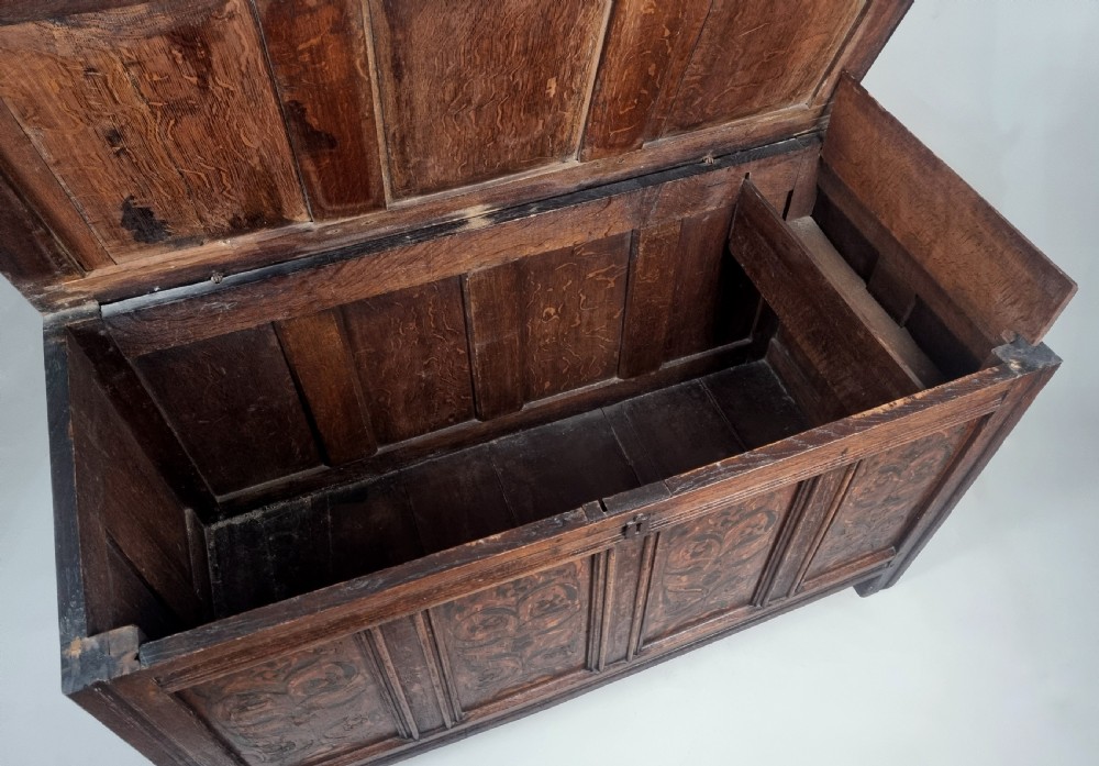 A 17th-century dark oak coffer featuring four front panels with floral marquetry inlay and a panelled hinged top. View VII