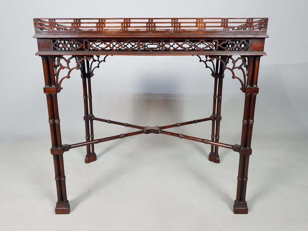 A dark padauk Chippendale style silver table featuring a pierced gallery rim, fretwork frieze, cluster legs, and turned stretchers. View III