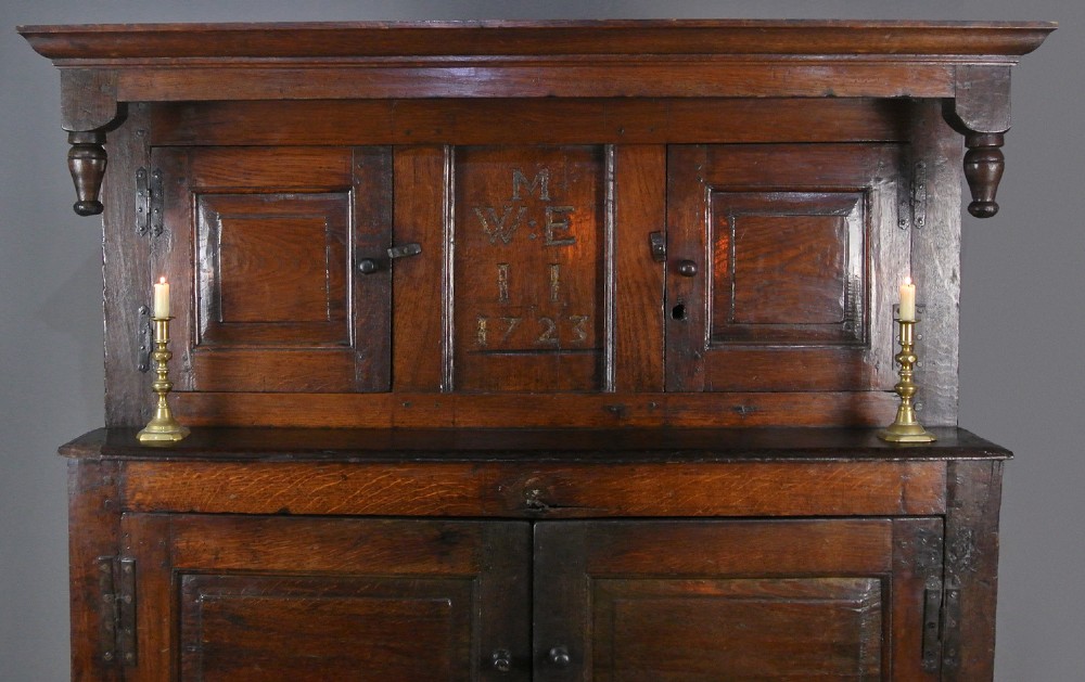 An 18th-century dark oak court cupboard featuring a carved date of 1723, upper recessed cabinet with drop finials, and fielded lower door panels. View II