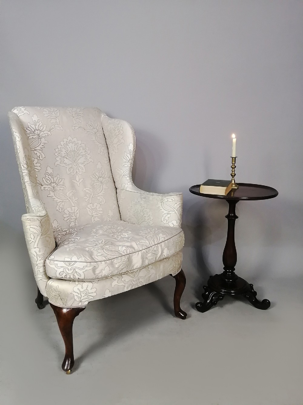 A 19th-century English wingback armchair upholstered in cream damask fabric with dark carved walnut cabriole front legs. View II