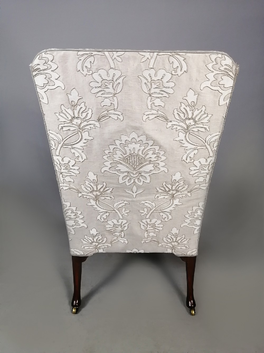 A 19th-century English wingback armchair upholstered in cream damask fabric with dark carved walnut cabriole front legs. View VI