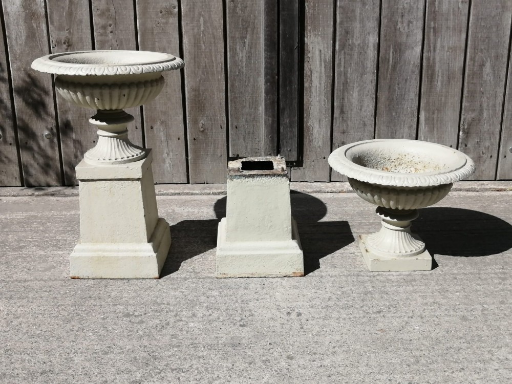 A pair of off-white painted cast iron garden urns with fluted rims and bases set upon matching square plinth pedestals. View IV