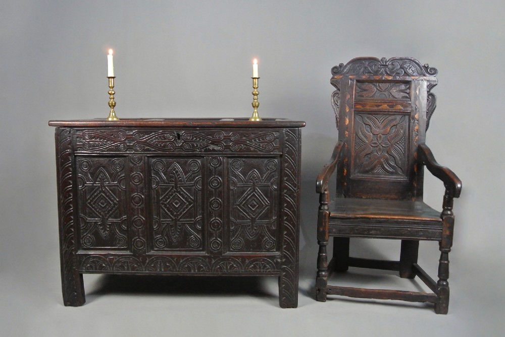 A dark oak Jacobean coffer featuring three carved front panels with diamond and circle motifs, a lunette carved top rail, and stile legs. View II