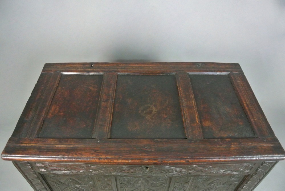 A dark oak Jacobean coffer featuring three carved front panels with diamond and circle motifs, a lunette carved top rail, and stile legs. View VI